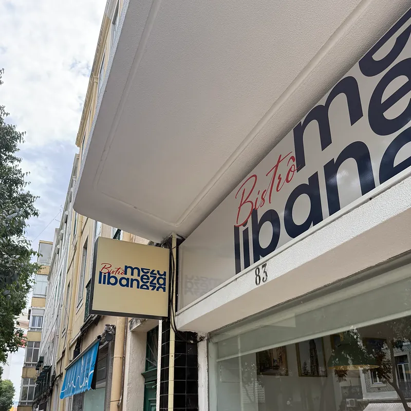 O letreiro Bistrô meza libaneza por cima da montra, com o número 83, e a placa de bandeira na fachada