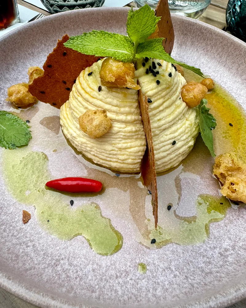Homus em espiral alta, com grão-de-bico frito, chips de sésamo, uma malagueta e hortelã