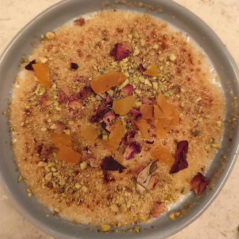 Pudim de leite caramelizado com pistácio picado, alperce seco e pétalas de rosa