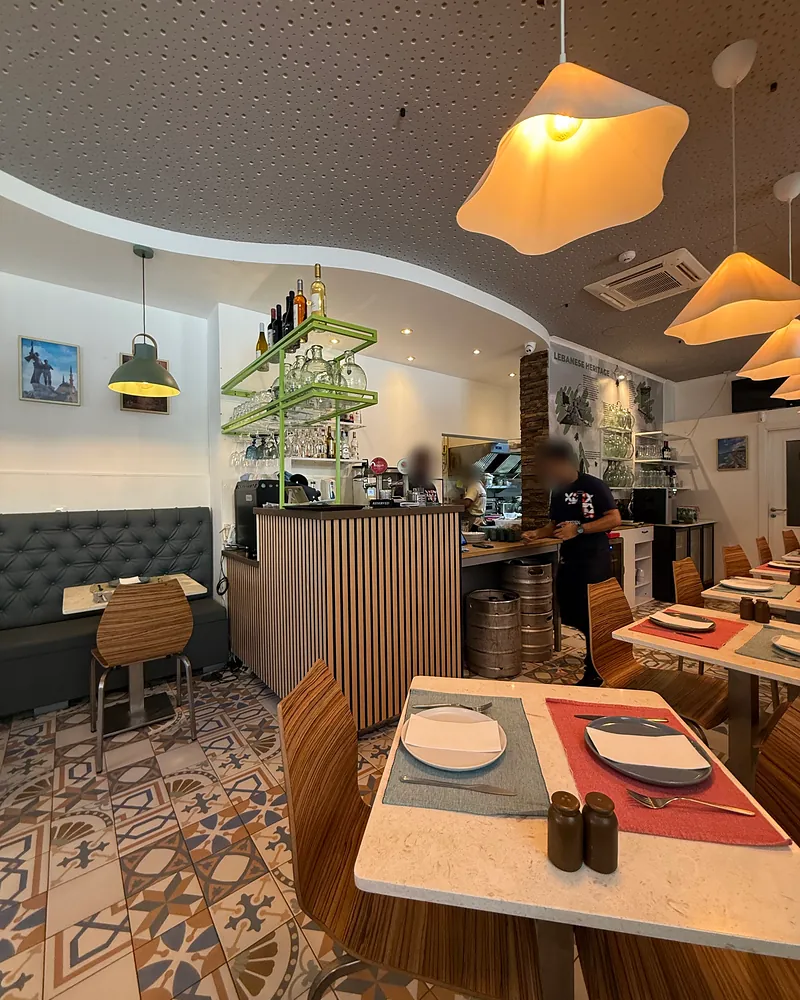 A sala, com chão de mosaico, candeeiros em forma de nuvem e o balcão de madeira com as garrafas numa prateleira verde